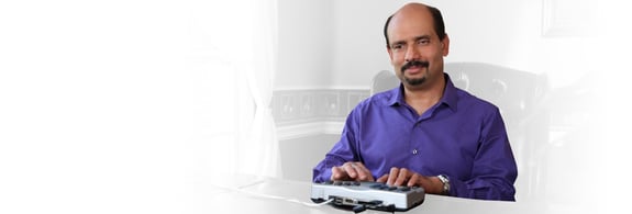 Adult male in a purple shirt using telebraille to communicate.